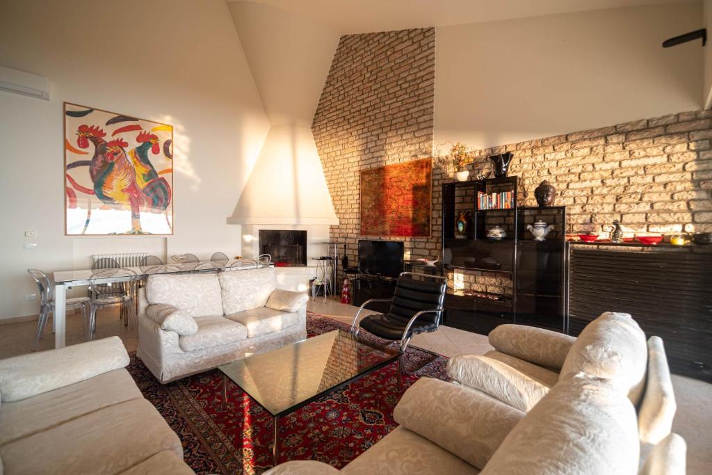 Il comprend un salon doté d'un mobilier blanc et d'un mur en briques. dans l'établissement Villa Elysium, à Torri del Benaco