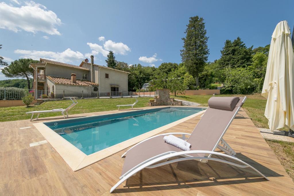 - une piscine avec une chaise à côté d'une maison dans l'établissement Villa Adelmo, à Pomarance