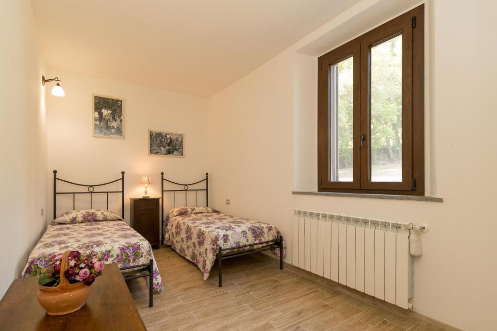 une chambre avec deux lits et une table et une fenêtre dans l'établissement Villa Adelmo, à Pomarance