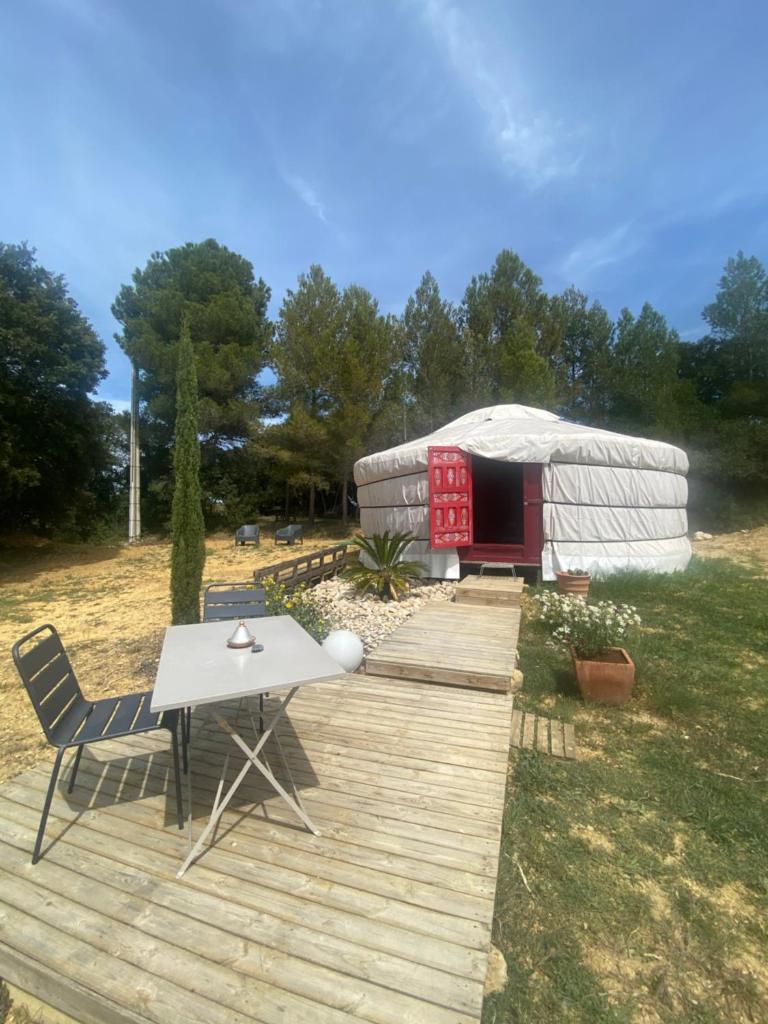 une terrasse en bois avec une table et une yourte dans l'établissement Yourte mongole, à Gignac