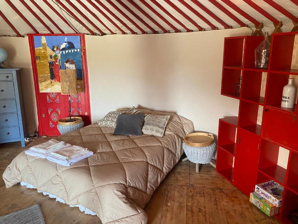 une chambre avec un lit et des étagères rouges dans l'établissement Yourte mongole, à Gignac
