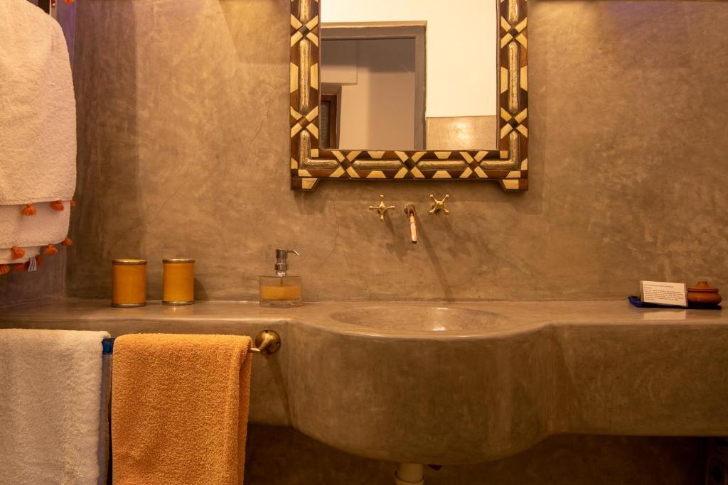 une salle de bain avec un lavabo, un miroir et des serviettes dans l'établissement Riad Dar Oulhoum, à Marrakech