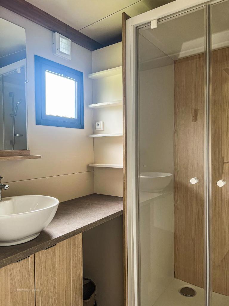 une salle de bain avec un lavabo et une douche en verre dans l'établissement Camping Onlycamp le Champ d'été, à Reyssouze