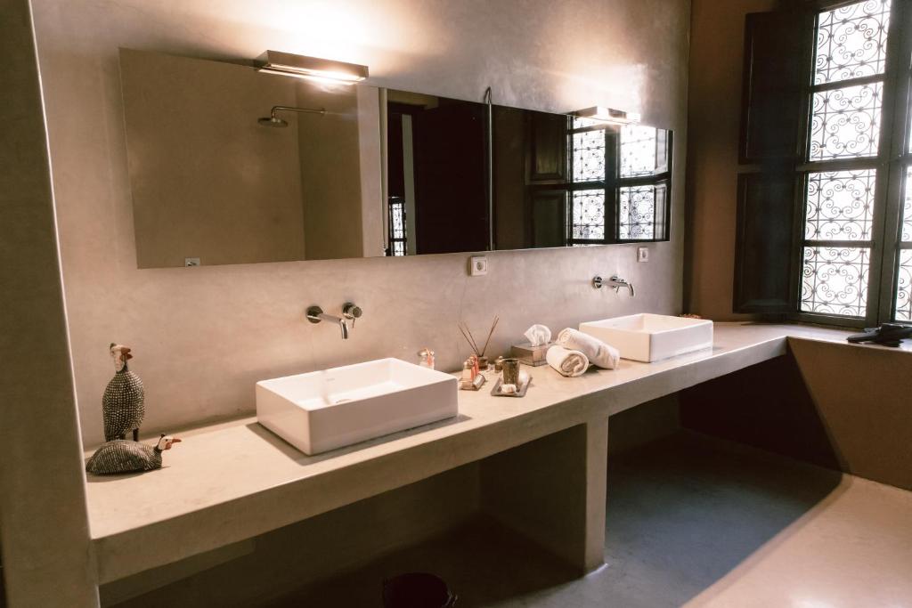 une salle de bain avec deux lavabos et un grand miroir dans l'établissement Riad K, à Marrakech