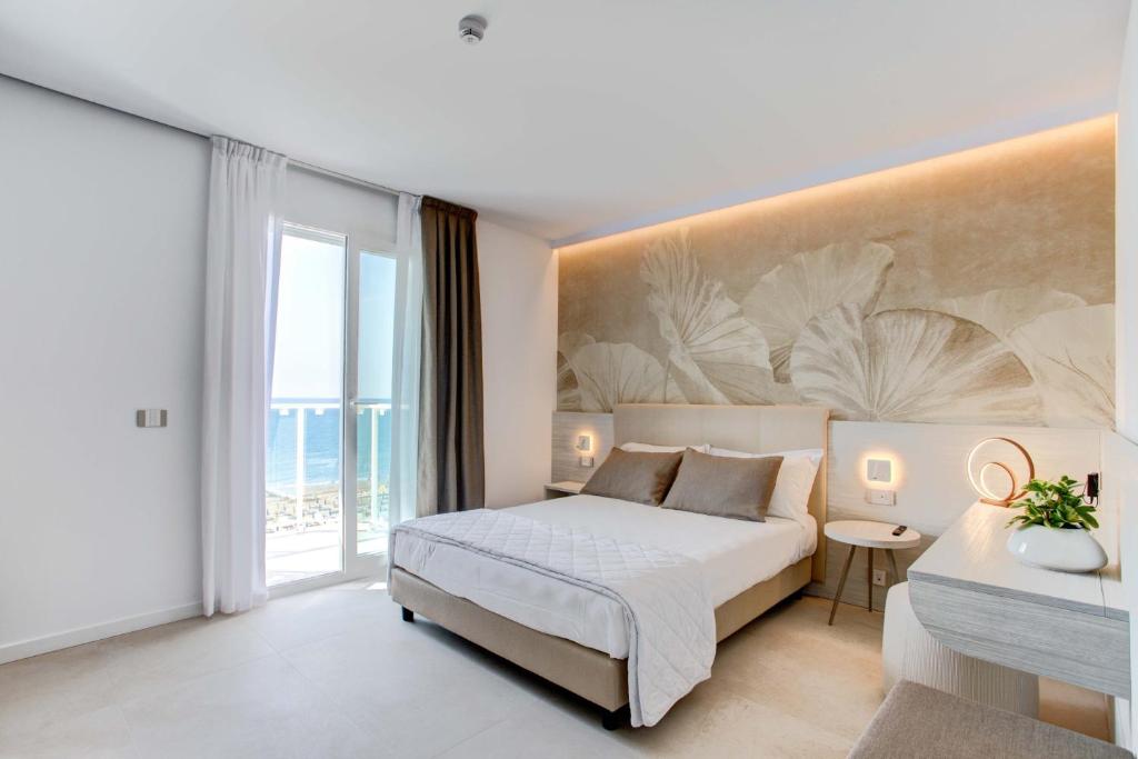 une chambre avec un lit et une grande fenêtre dans l'établissement Hotel Mirafiori, à Lido di Jesolo