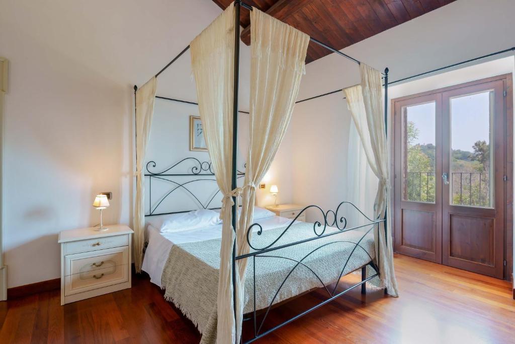 une chambre avec un lit à baldaquin et une fenêtre dans l'établissement tHE Italian Dream Villa - Pool, Spa & Wine, à Boceto