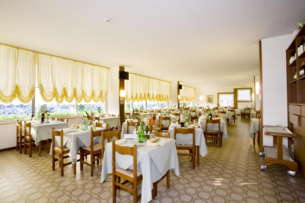 une salle à manger avec des tables et des chaises blanches dans l'établissement Hotel Metropol, à Caorle