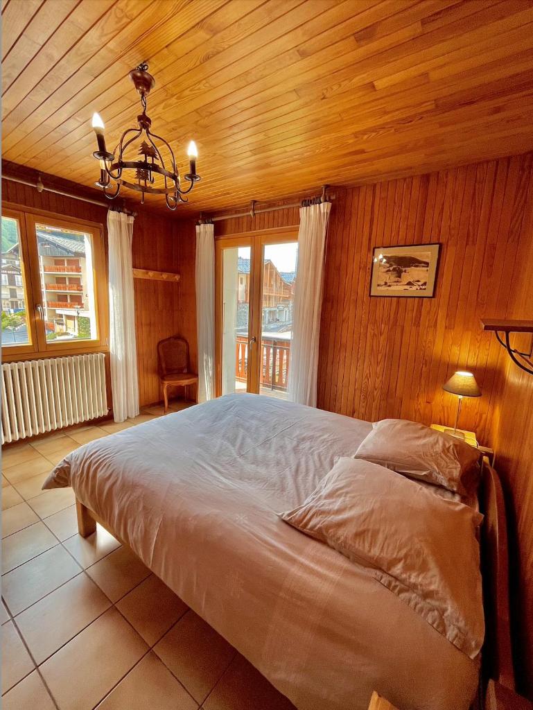 une chambre avec un grand lit avec un plafond en bois dans l'établissement Résidences Delavay La Cordée, aux Gets