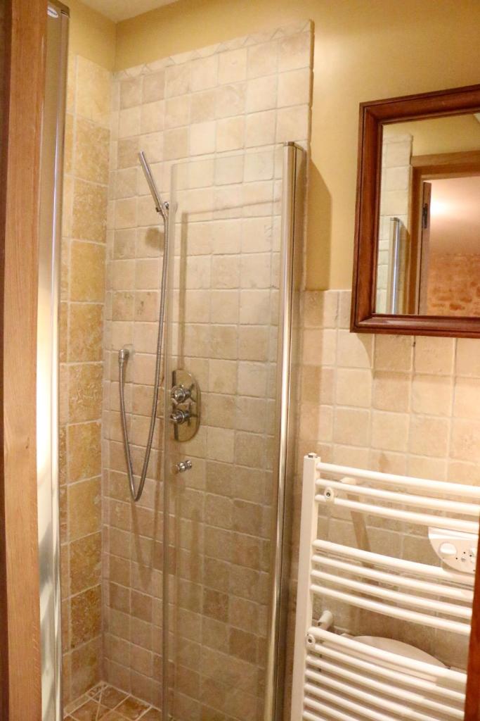 une douche avec une porte vitrée dans une salle de bain dans l'établissement Les Perroutis, à Saint-Alvère