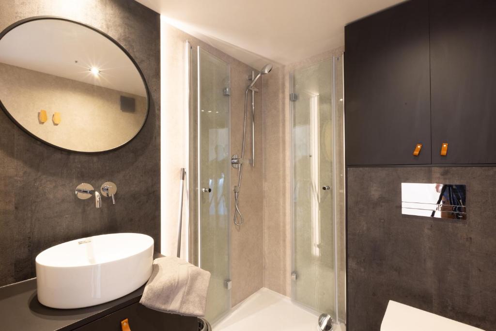 une salle de bain avec un lavabo et une douche avec un miroir dans l'établissement Les Dômes des Gorges, à Ruoms