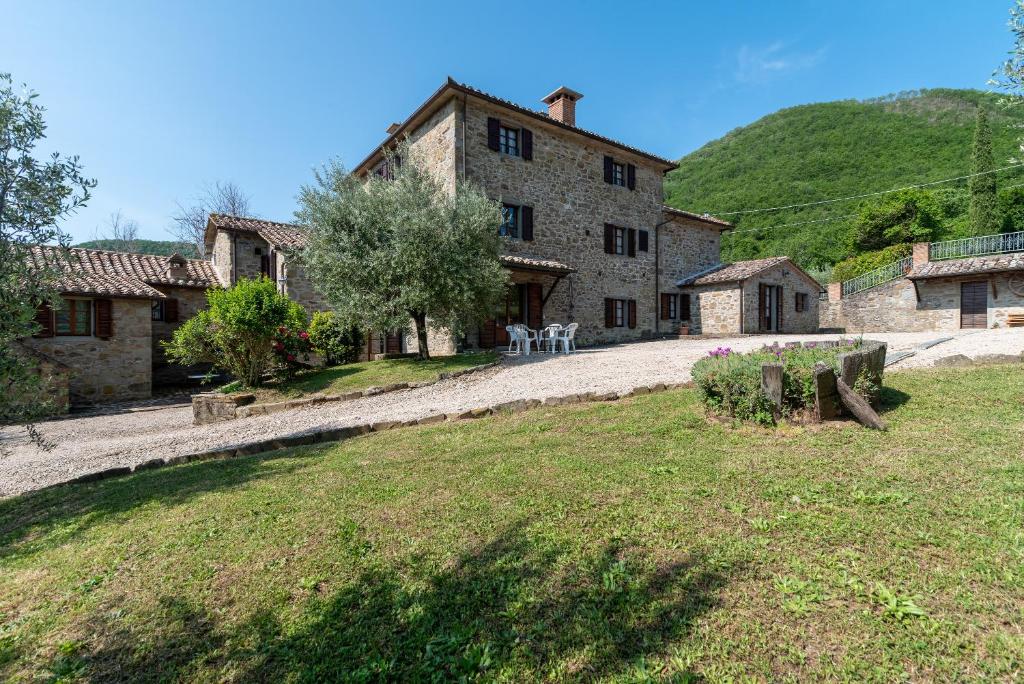 - un grand bâtiment en pierre avec une table et des chaises dans une cour dans l'établissement Villa Agriturismo Cuiano - Pierle, à Cortone