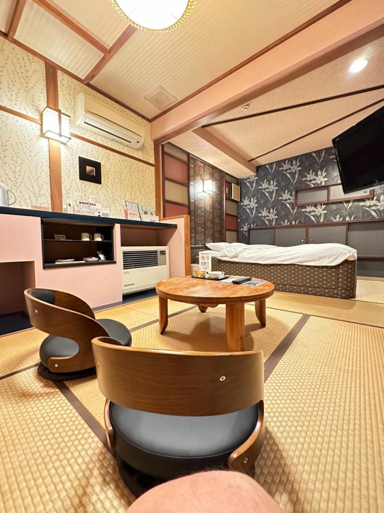 un salon avec un lit, une table et des chaises dans l'établissement ホテル水明, à Koriyama