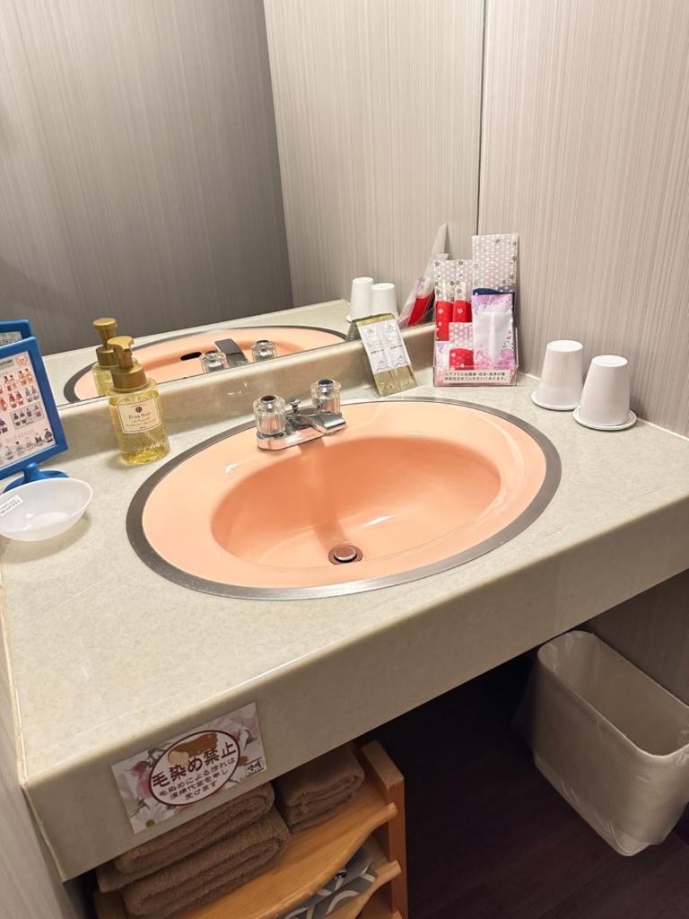 un comptoir de salle de bain avec un lavabo et un miroir dans l'établissement ホテル水明, à Koriyama 3 autres photos