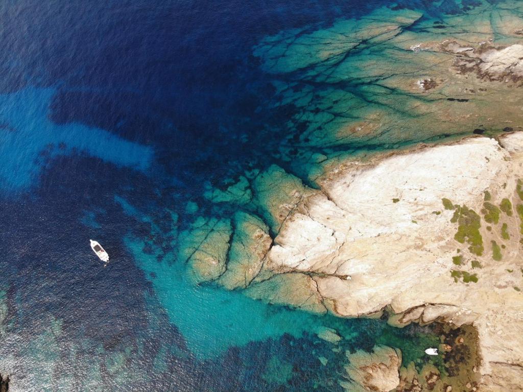 vue aérienne d'un bateau dans l'eau près d'une falaise dans l'établissement Eco Village Baia Delle Ginestre, à Teulada