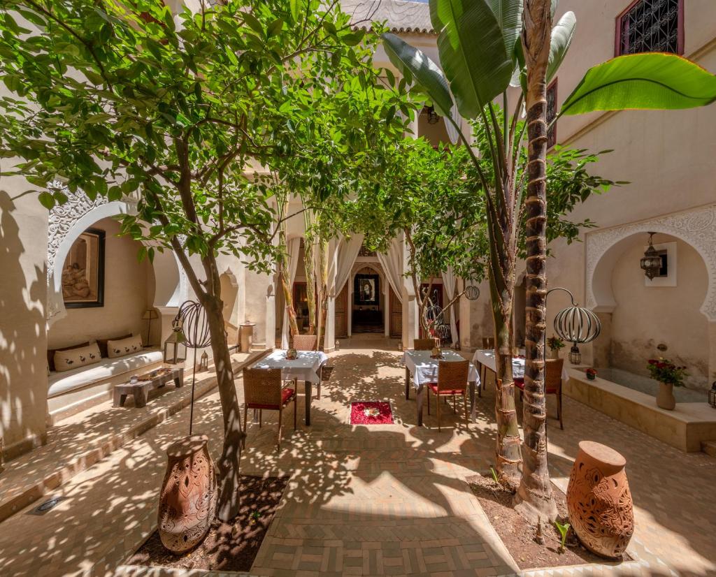 une cour avec des arbres, des tables et des chaises dans l'établissement Riad Dar Karma, à Marrakech
