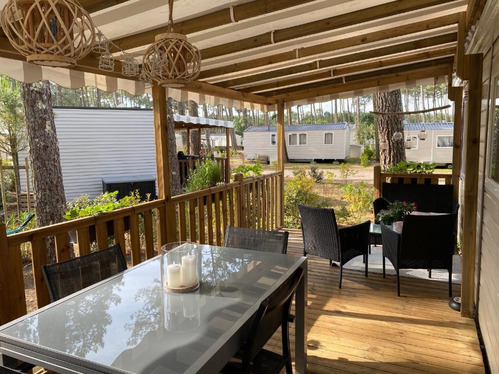 un patio avec une table et des chaises sur une terrasse dans l'établissement Charmant Mobilhome avec espace vert au milieu des pins proche de la plage sur le camping "les dunes de contis", à Saint-Julien-en-Born
