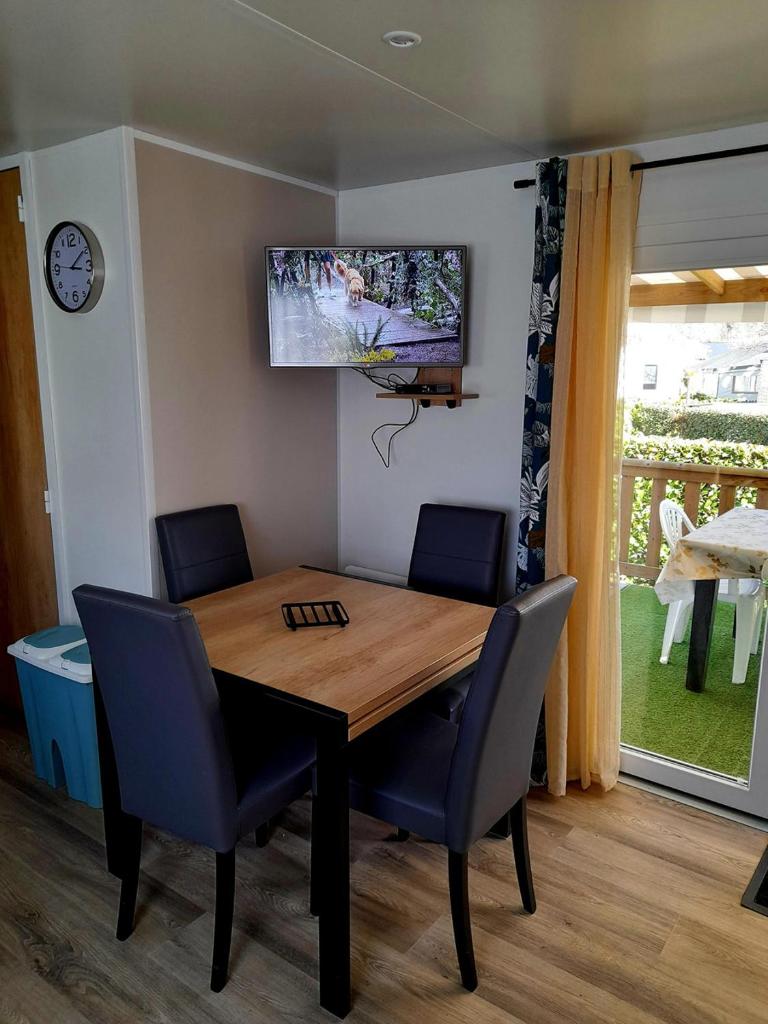 une table à manger avec des chaises et une télévision murale dans l'établissement L EVASION, à Pont-Aven