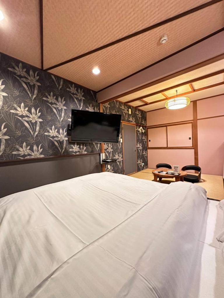une chambre avec un lit et une télévision sur un mur dans l'établissement ホテル水明, à Koriyama