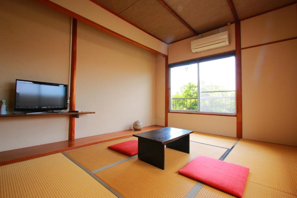 un salon avec une table et une télévision dans l'établissement Family Ryokan Kawakyu with Showa Retro, private hot spring, à Ibusuki