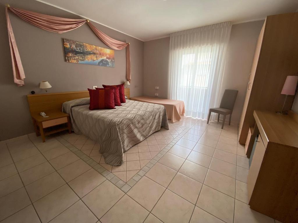 Cette chambre comprend un lit avec des oreillers rouges. dans l'établissement Hotel Acquario, à Campomarino