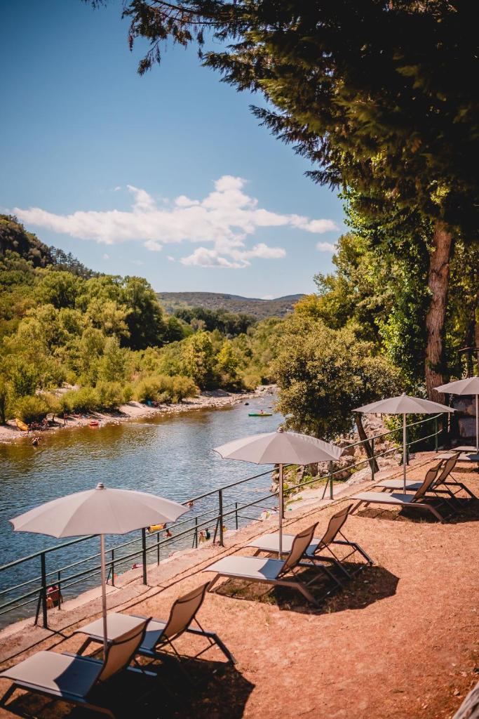- une plage avec des chaises longues et des parasols à côté d'une rivière dans l'établissement Rives d'Arc, à Vallon-Pont-dʼArc