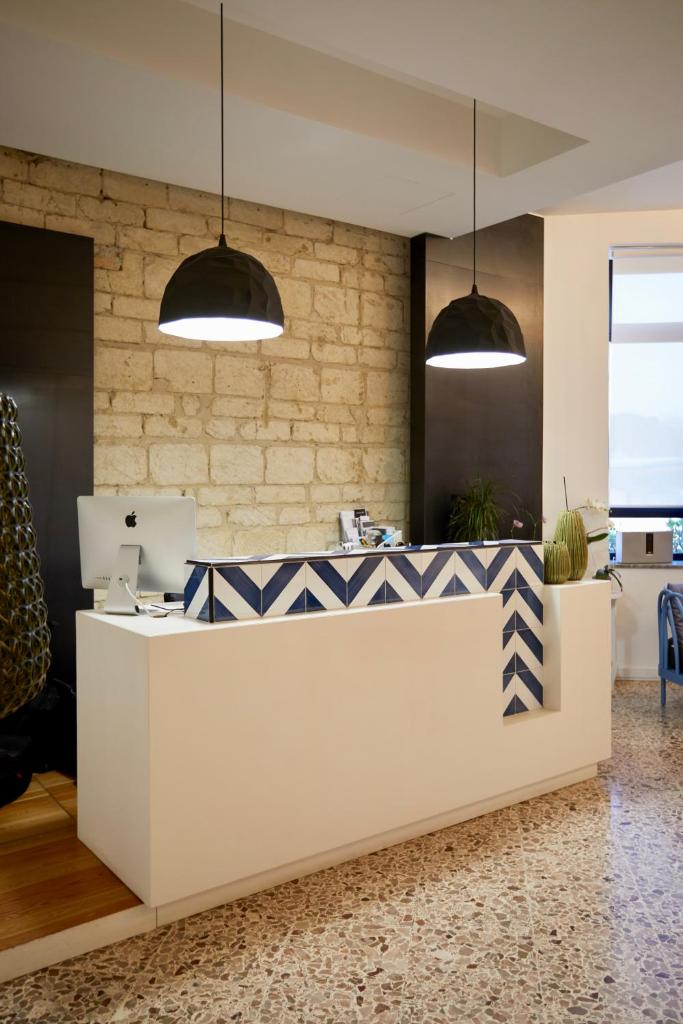 - un hall avec un comptoir blanc et bleu et deux lampes pendant dans l'établissement Hotel Mandetta - Adults Only, à Paestum