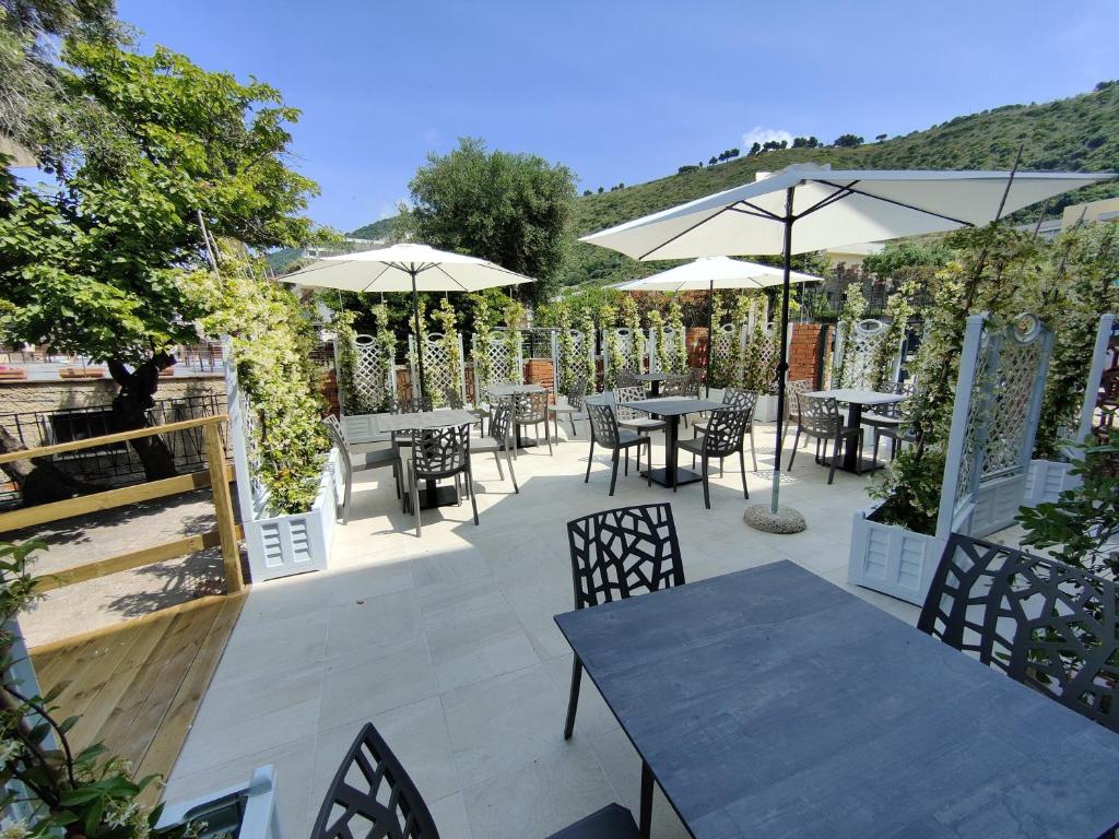 un patio avec tables, chaises et parasols dans l'établissement Hotel Acciaroli, à Acciaroli 73 autres photos