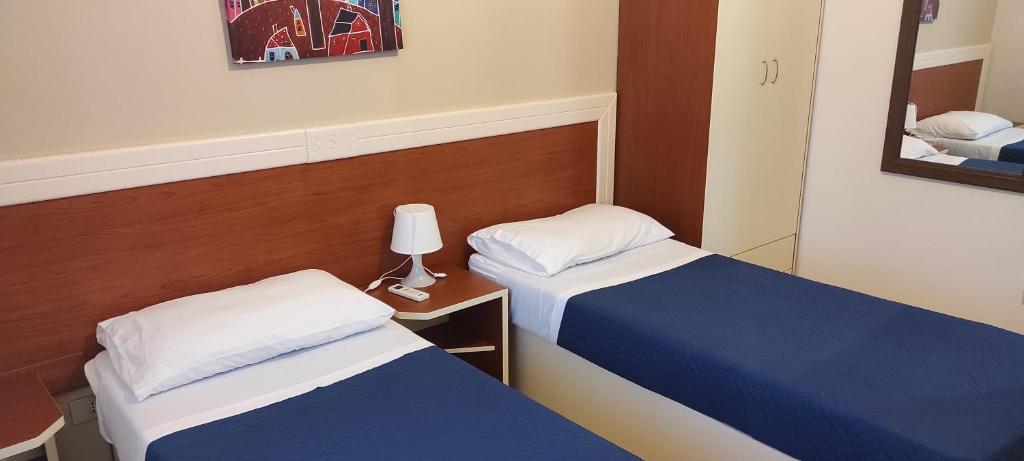 une chambre d'hôtel avec deux lits et un miroir dans l'établissement Residence Santa Barbara, à San Ferdinando