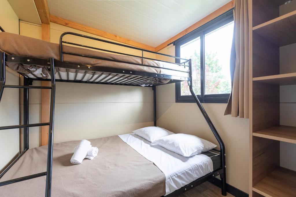 une chambre avec un lit superposé et une fenêtre dans l'établissement Huttopia Les Châteaux, à Bracieux 19 autres photos
