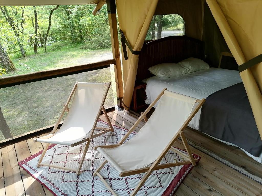 - 2 chaises pliantes et un lit dans une tente dans l'établissement Camping L'Ondine de Provence, à La Motte-Chalançon