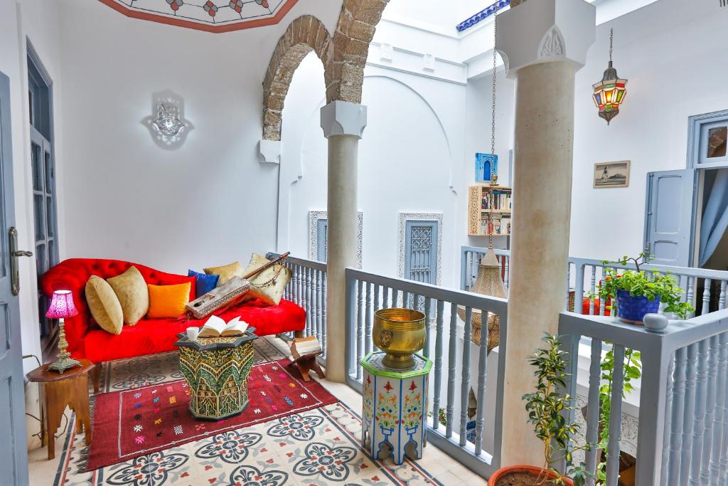 un salon avec un canapé rouge sur un balcon dans l'établissement Riad Alech, à Essaouira