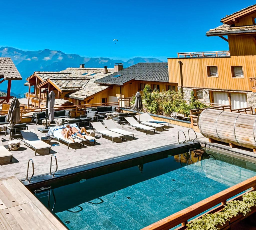 - une piscine dans un complexe avec des chaises longues dans l'établissement Grandes Rousses Hotel & Spa, à L'Alpe-d'Huez