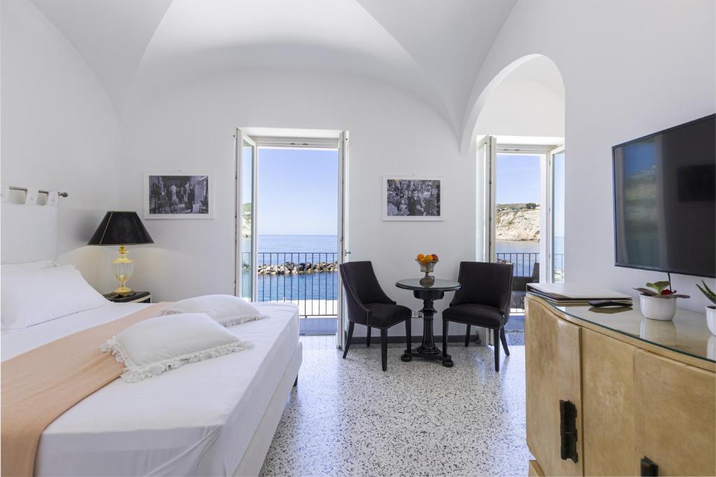 une chambre avec un lit et une table avec des chaises dans l'établissement Roccobarocco Boutique Hotel, à Ischia
