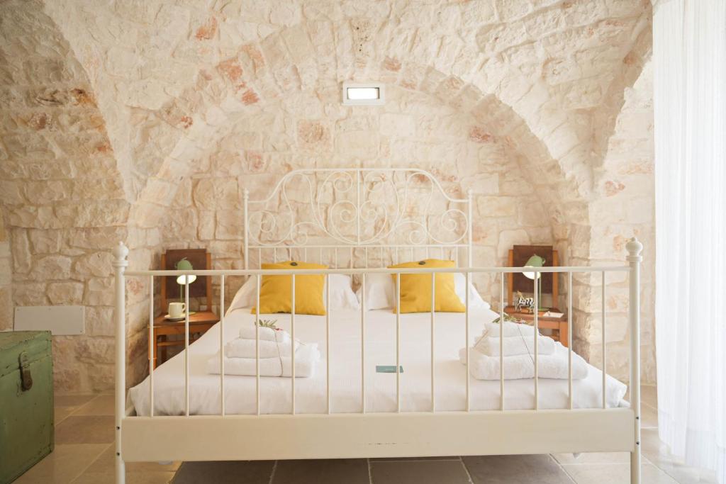 une chambre avec un lit dans un mur de pierre dans l'établissement Trullo Delori with infinity Pool, à Villa Castelli