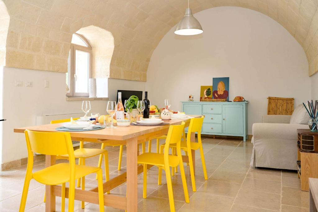 une cuisine avec une table en bois et des chaises jaunes dans l'établissement Trullo Delori with infinity Pool, à Villa Castelli