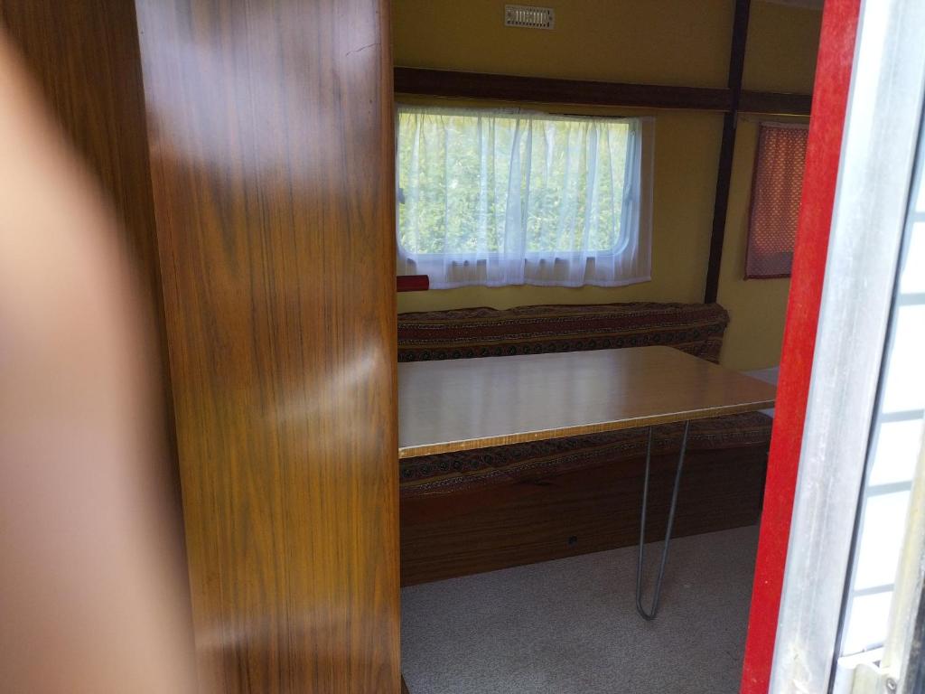 Cette chambre dispose d'une table et d'une fenêtre. dans l'établissement Camping La Fôret du Morvan Vintage caravan, à Larochemillay