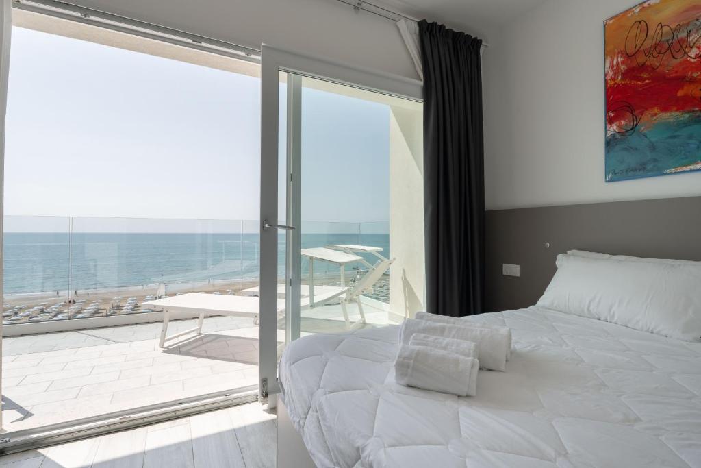 une chambre avec un grand lit blanc et un balcon dans l'établissement Hotel Boston 3 Stelle Superior Frontemare, à Lido di Jesolo