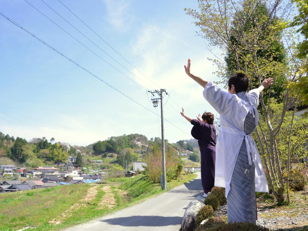 deux femmes debout sur un rocher avec leurs bras en l'air dans l'établissement Fudouonsen Sawaya, à Shimojo mura