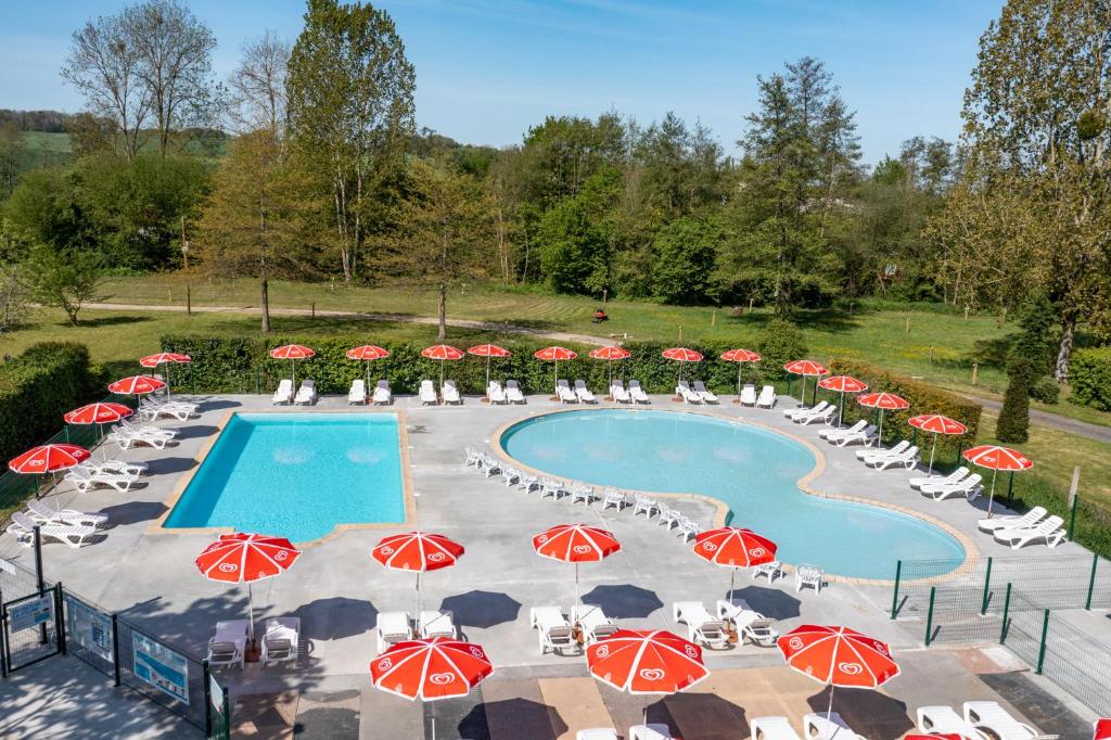 une piscine avec des parasols et des chaises rouges et blancs dans l'établissement Camping Country Park Crecy La Chapelle - Site Officiel - Next to Disneyland Paris, à Crécy-la-Chapelle