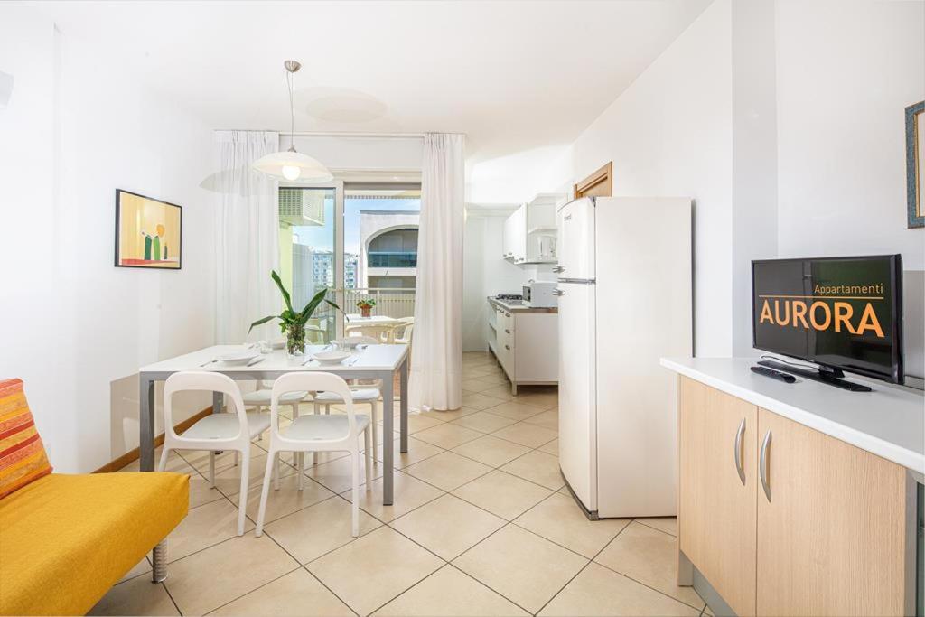 une cuisine avec une table et un réfrigérateur blanc dans l'établissement Appartamenti Aurora, à Bibione