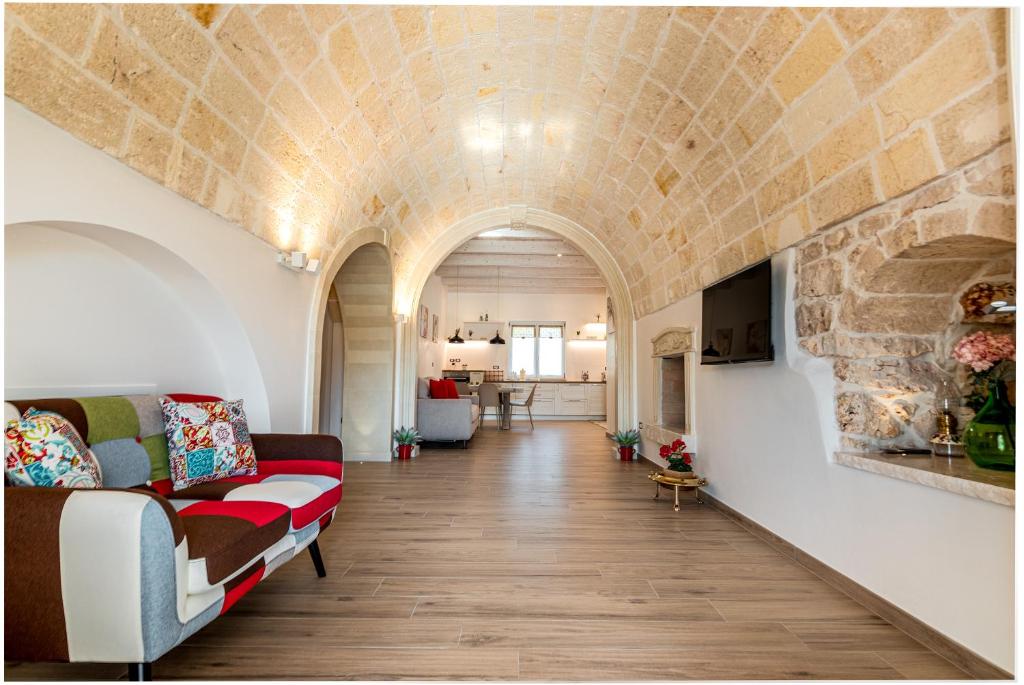 un salon avec un canapé et un mur en pierre dans l'établissement La Carezza del Sole - Private Villa, à Francavilla Fontana