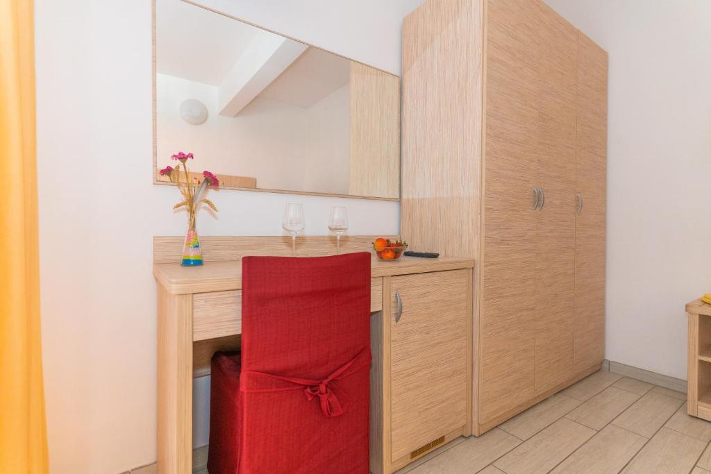 une cuisine avec une table en bois et une chaise rouge dans l'établissement Hotel Croce Del Sud, à Rimini