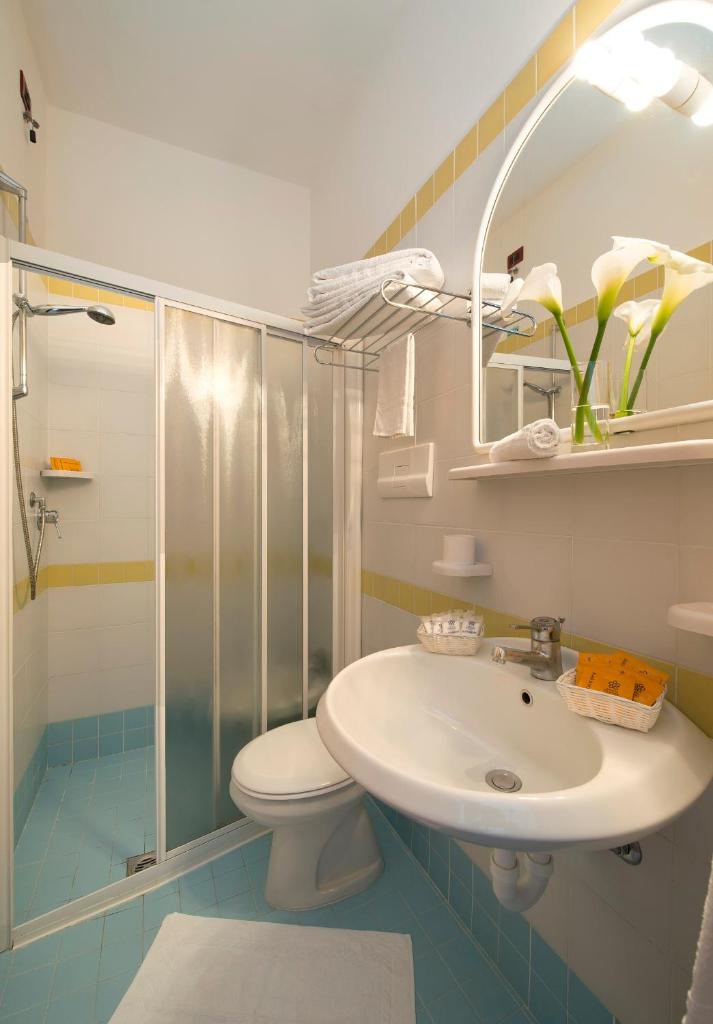 une salle de bain avec un lavabo, des toilettes et une douche dans l'établissement Hotel Pillon, à Bibione