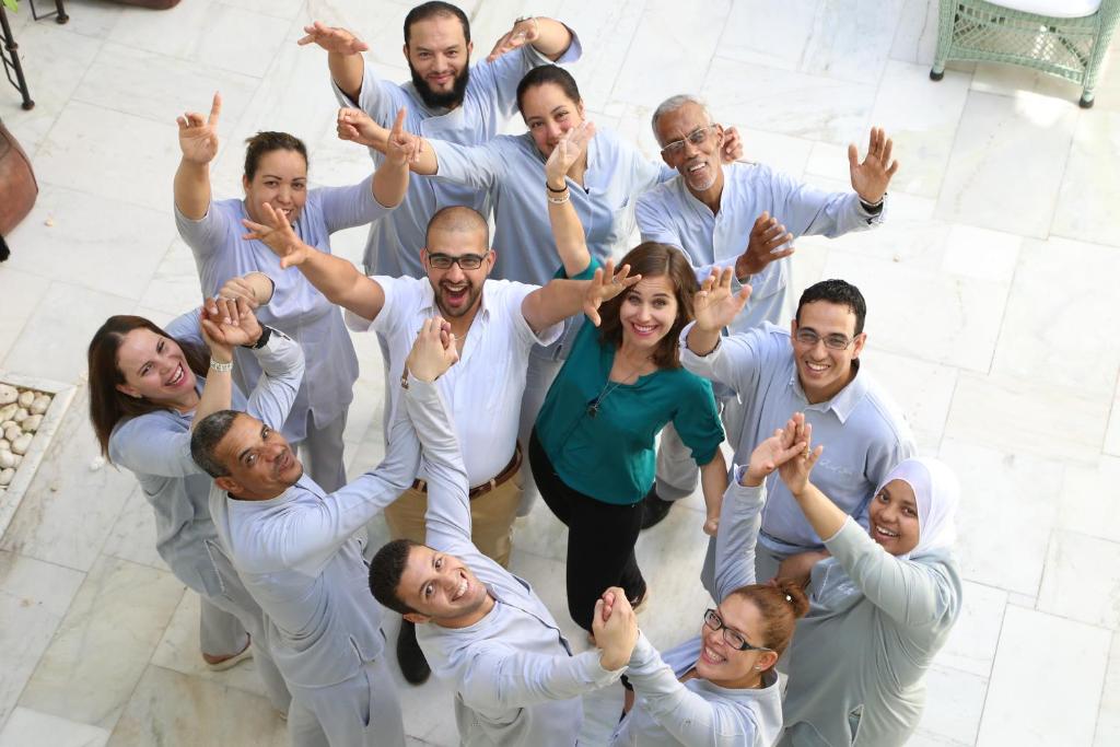 Un groupe de personnes se tenant dans un cercle, les mains levées dans l'établissement Riad Idra, à Marrakech