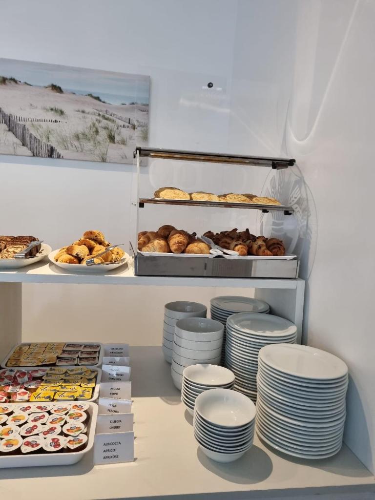 une boulangerie avec des assiettes et des pâtisseries sur une étagère dans l'établissement Hotel Serenella, à Lido di Jesolo