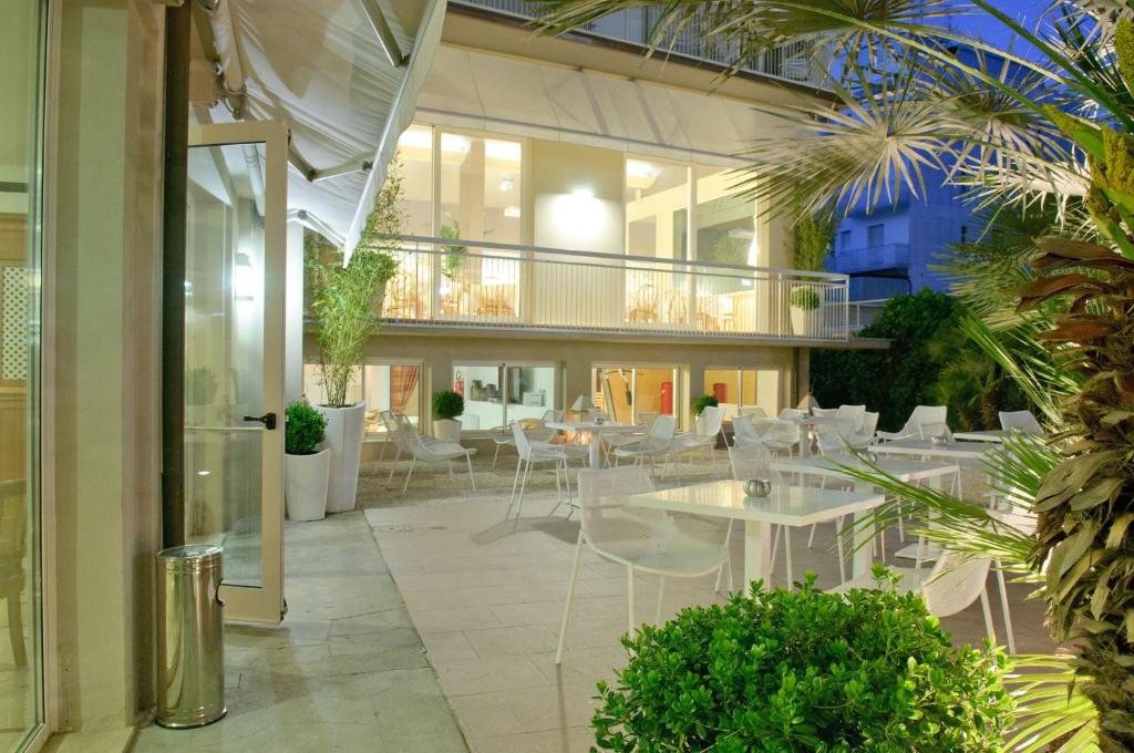 un patio avec des tables et des chaises blanches dans un bâtiment dans l'établissement HOTEL TRIONFAL - Fronte Mare - Vicinissimi al Centro, à Milano Marittima
