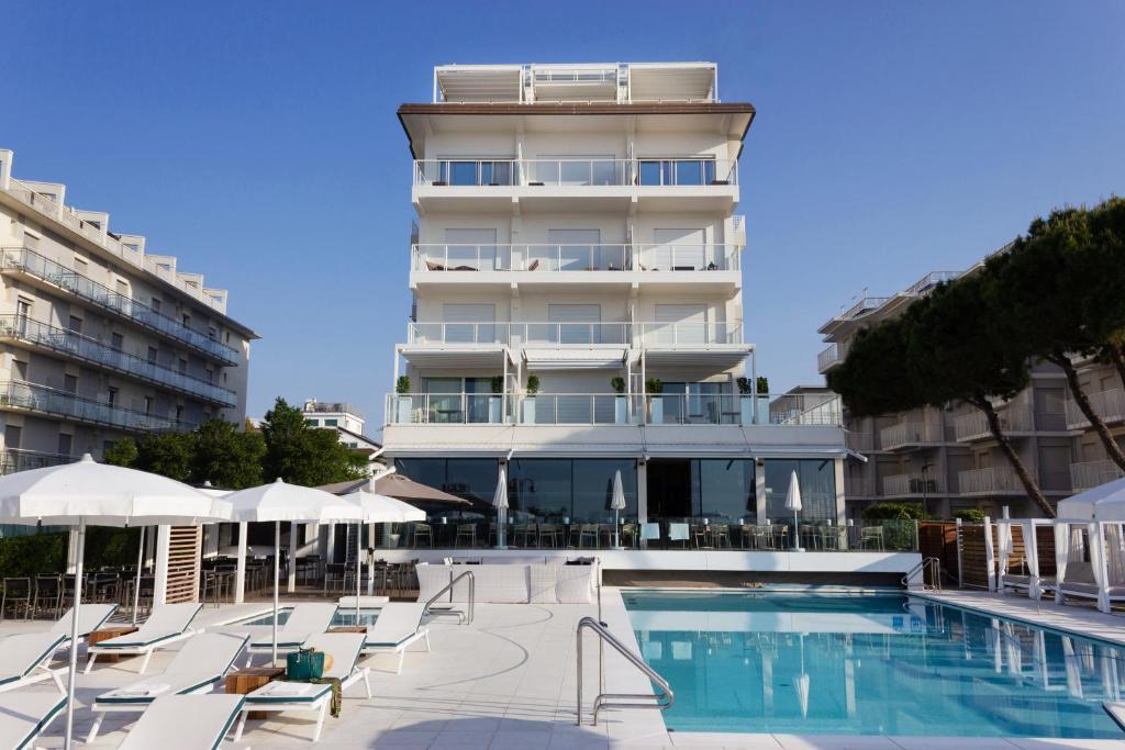 un hôtel avec une piscine devant un bâtiment dans l'établissement Hotel Ril, à Lido di Jesolo