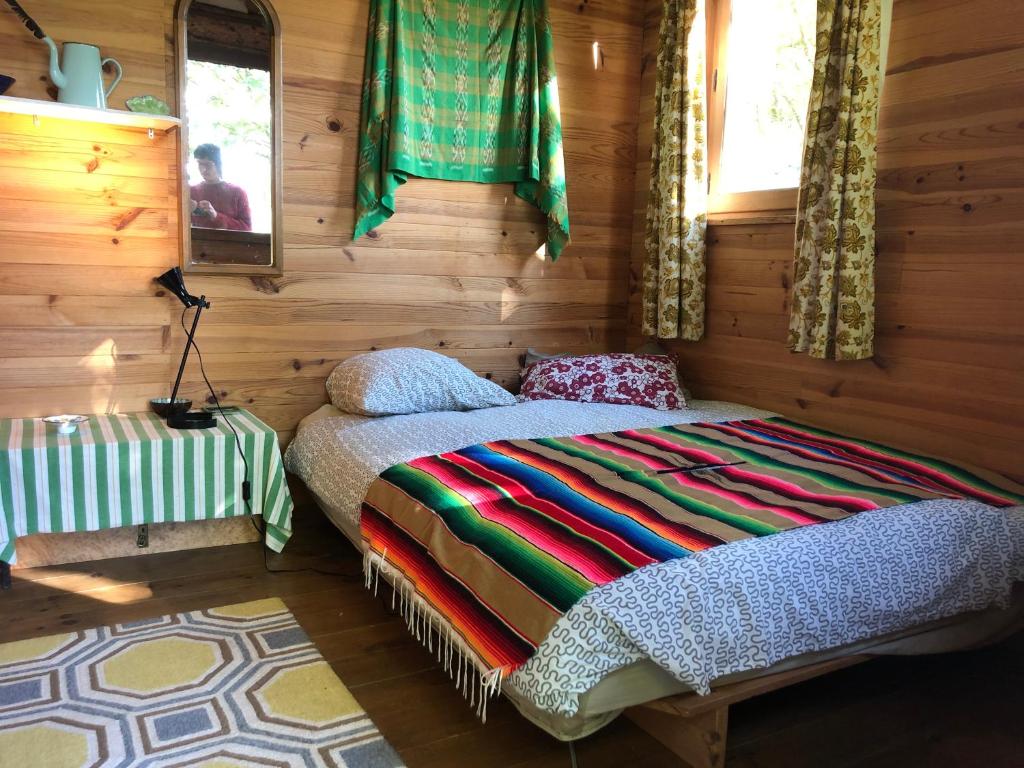 une chambre avec un lit dans une cabane en rondins dans l'établissement Fenêtre sur les Pyrénées, à Soulan