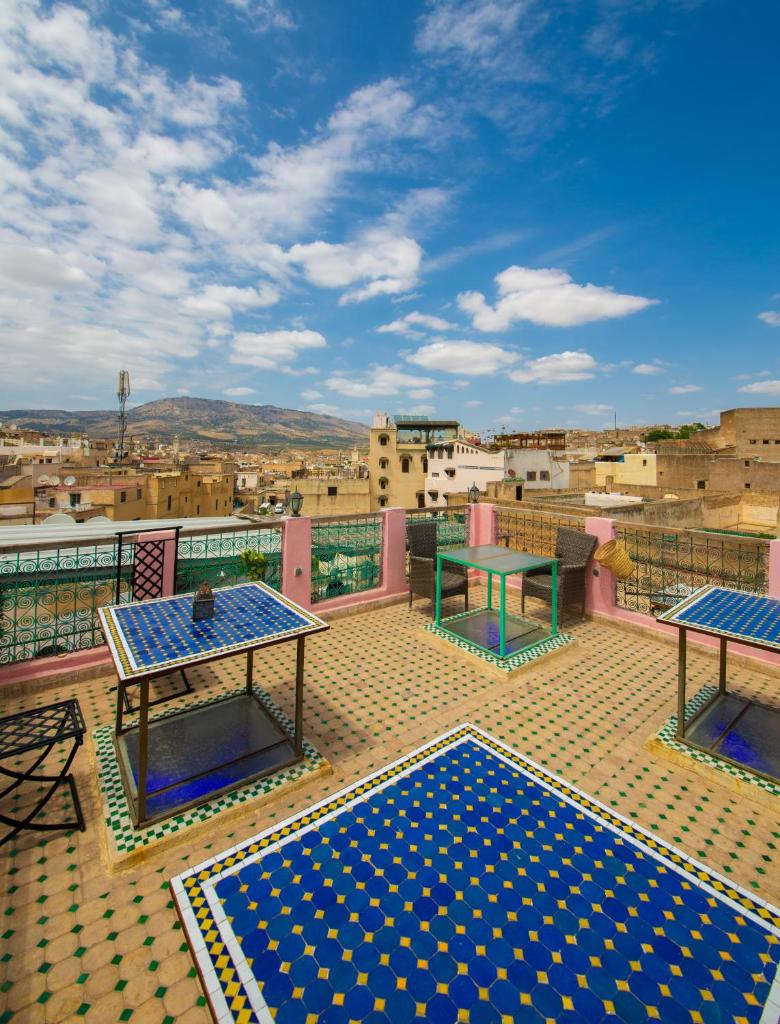 un balcon avec deux tables et une vue sur une ville dans l'établissement Riad Fes Hayat - Confort Stay, à Fès