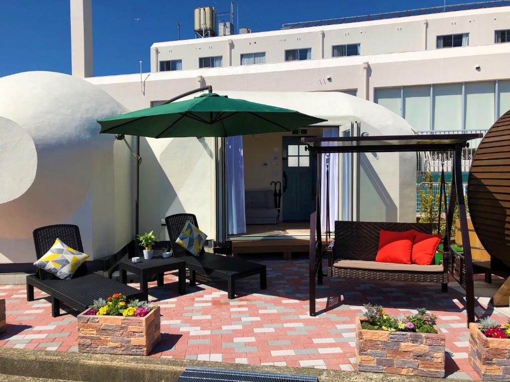 une terrasse avec une balançoire et un parasol dans l'établissement The Gran Resort Amanohashidate, à Miyazu